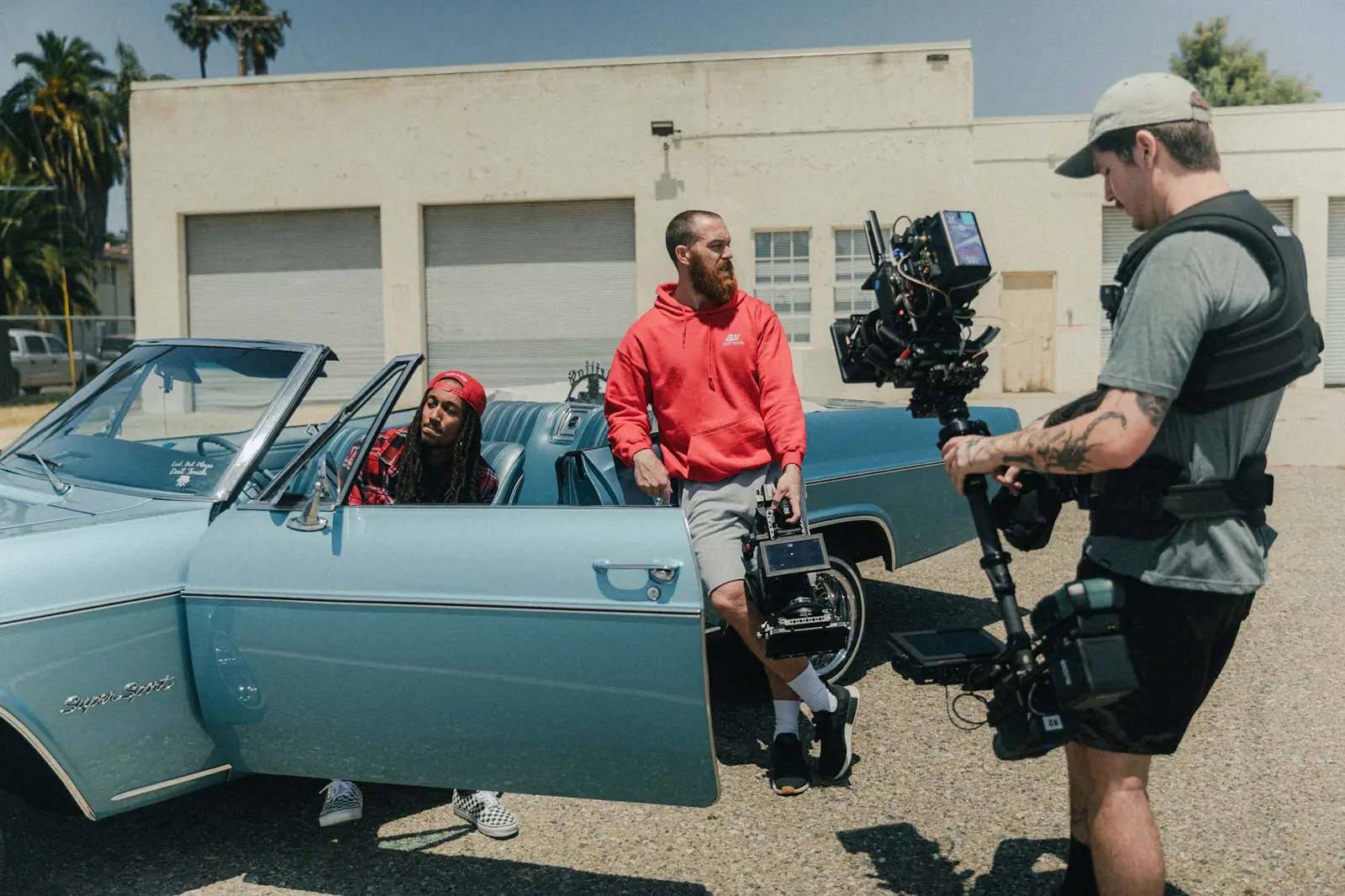 A camera crew filming beside a vintage convertible on a city street