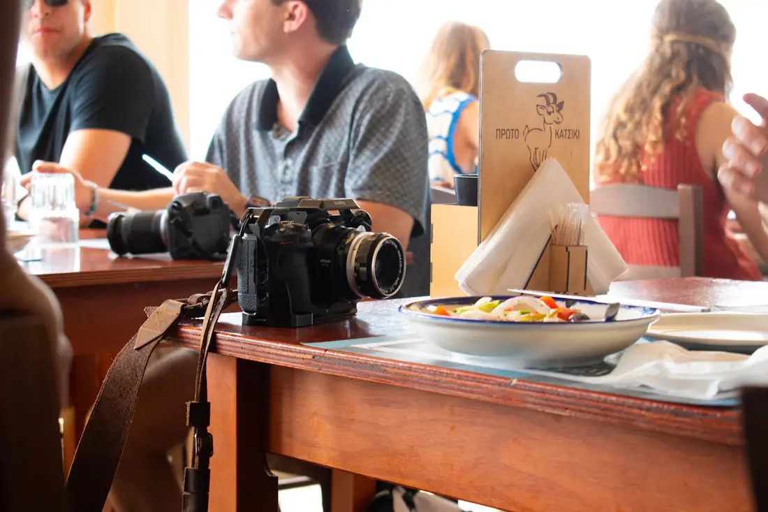 A crew member at a table with a plate of food beside camera gear