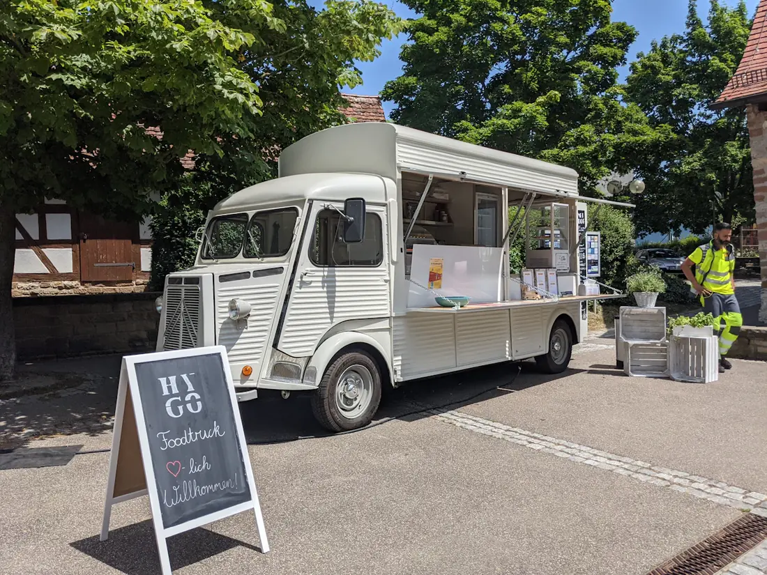 A small white catering van parked on a plaza